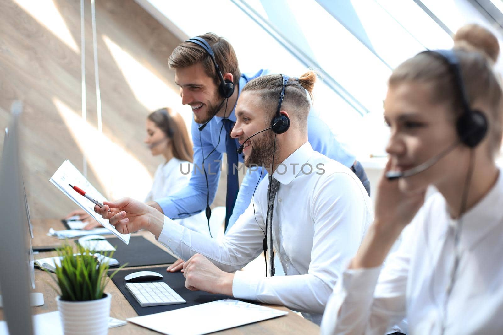 Phone operator working at call centre office helping his colleague