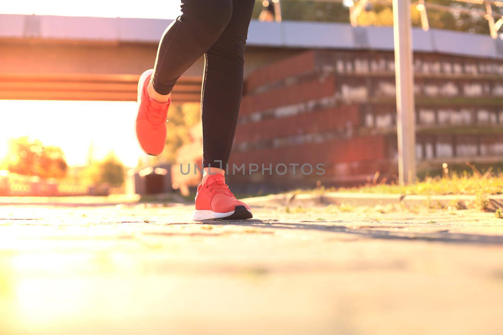 Close up of young woman in sports shoes jogging while exercising outdoors