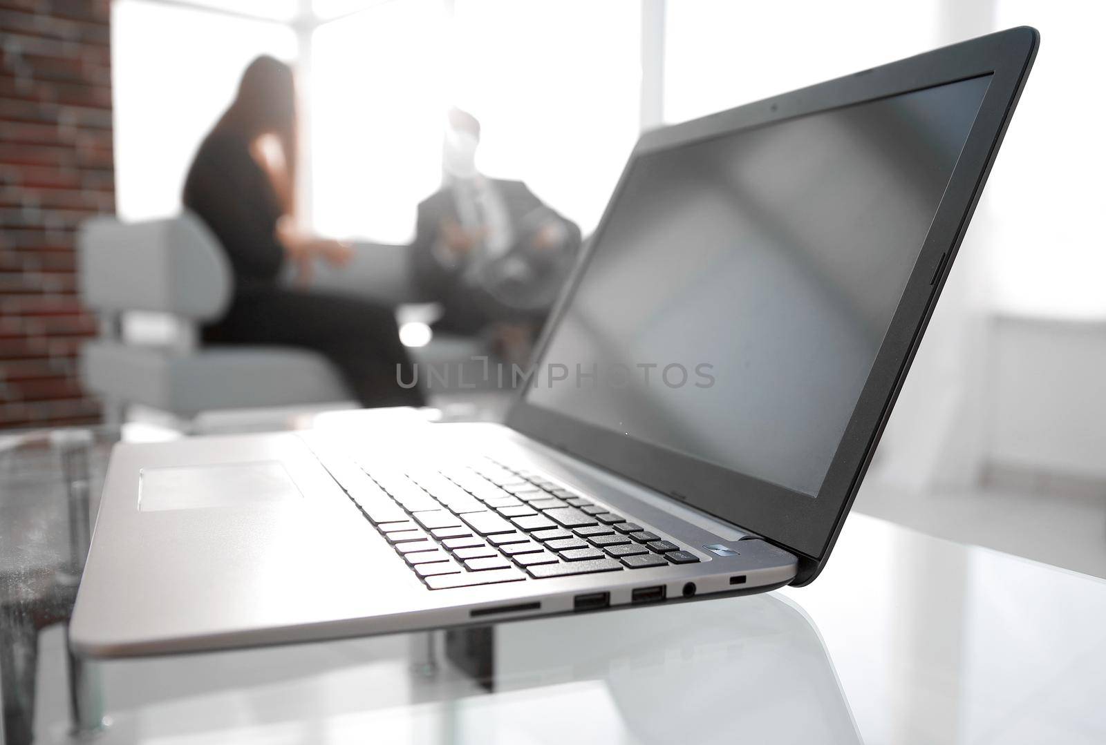 Focus on laptop on the table. Blurred people on background. by asdf