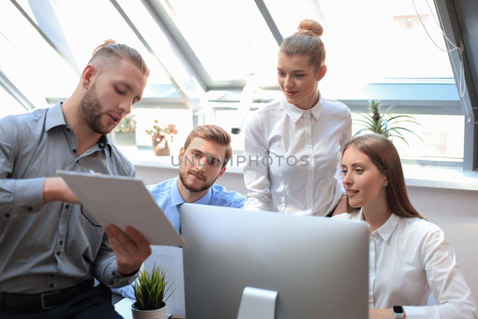 Startup business team on meeting in modern bright office interior brainstorming, working on tablet and PC computers