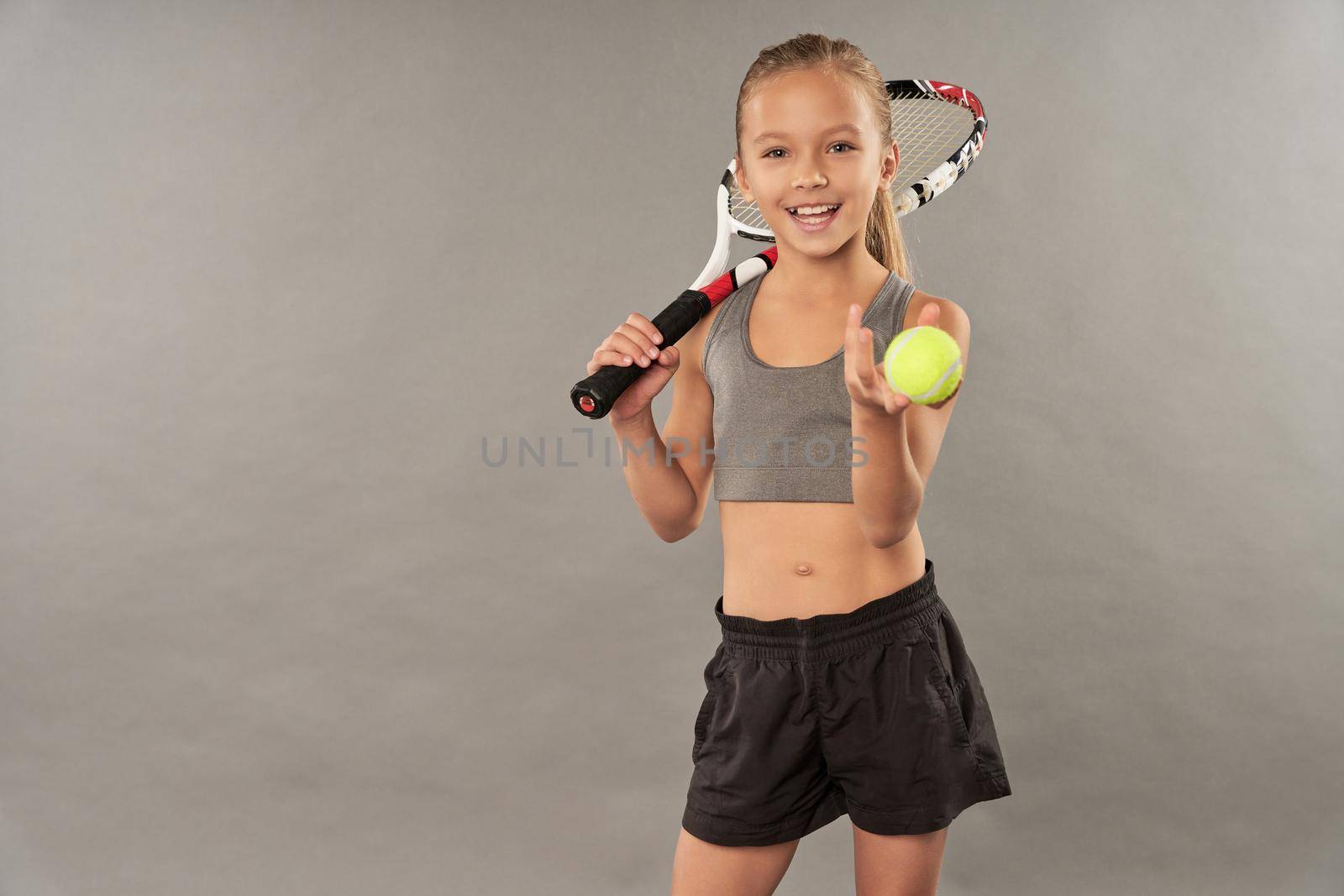 Little tennis player holding racket and yellow ball by friendsstock