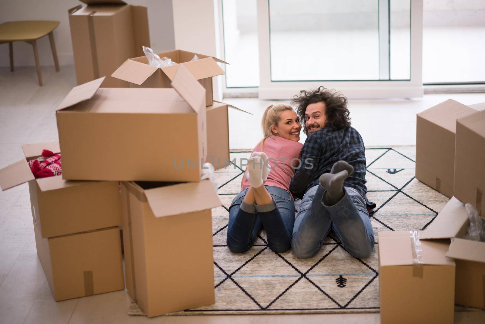 Young couple in love moving in a new flat, lying on the floor and surfing the web on a tablet computer in search of new redecoration ideas