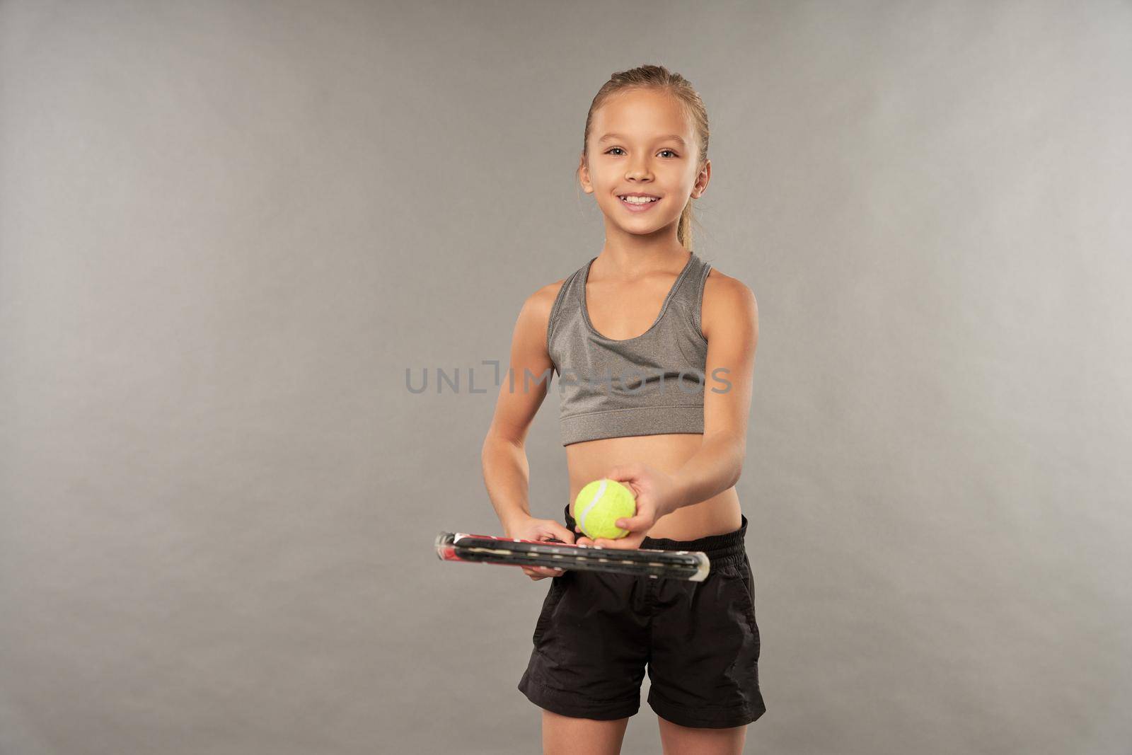 Adorable joyful girl in sportswear playing tennis by friendsstock