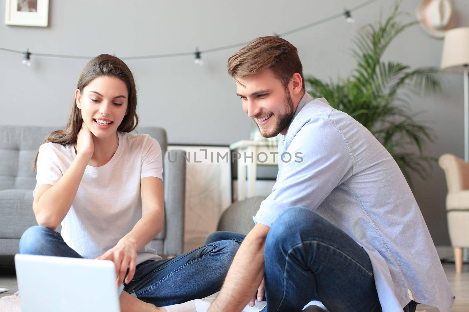 Young couple doing some online shopping at home, using a laptop on floor
