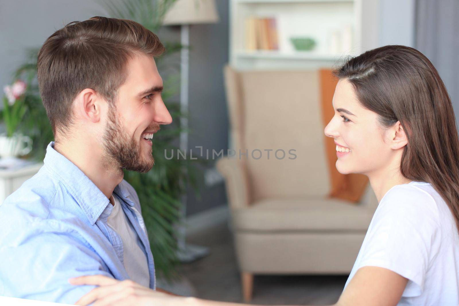 Side view of a couple talking sitting on a couch and looking each other at home