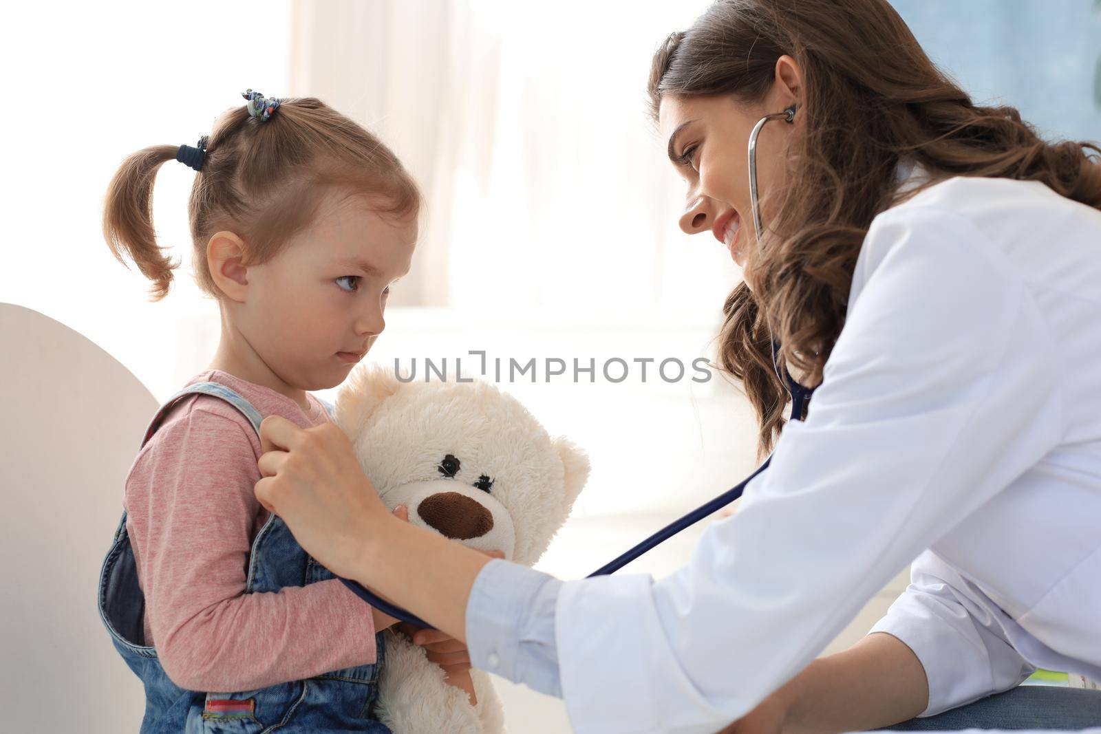 Little girl at the doctor for a checkup. Doctor woman auscultate the heartbeat of the child. by tsyhun