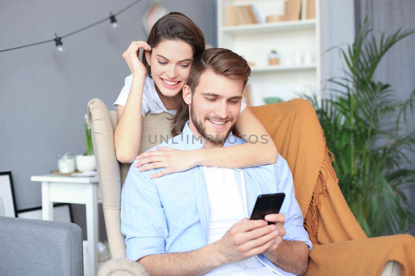 Young couple doing some online shopping at home, using smart phone on the sofa