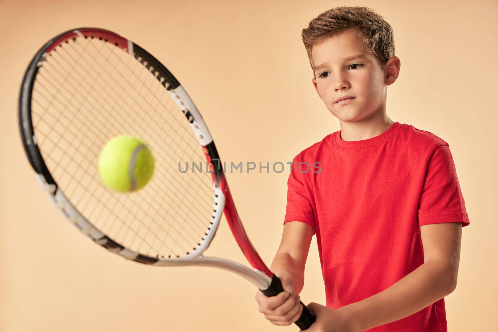 Adorable boy in red shirt playing tennis by friendsstock