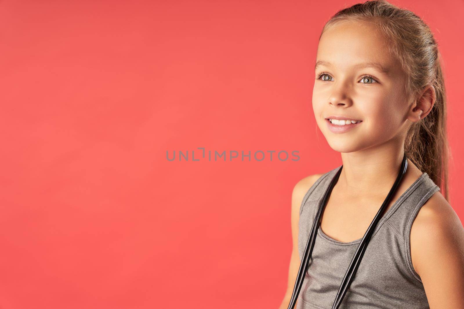 Adorable female child standing against red background by friendsstock