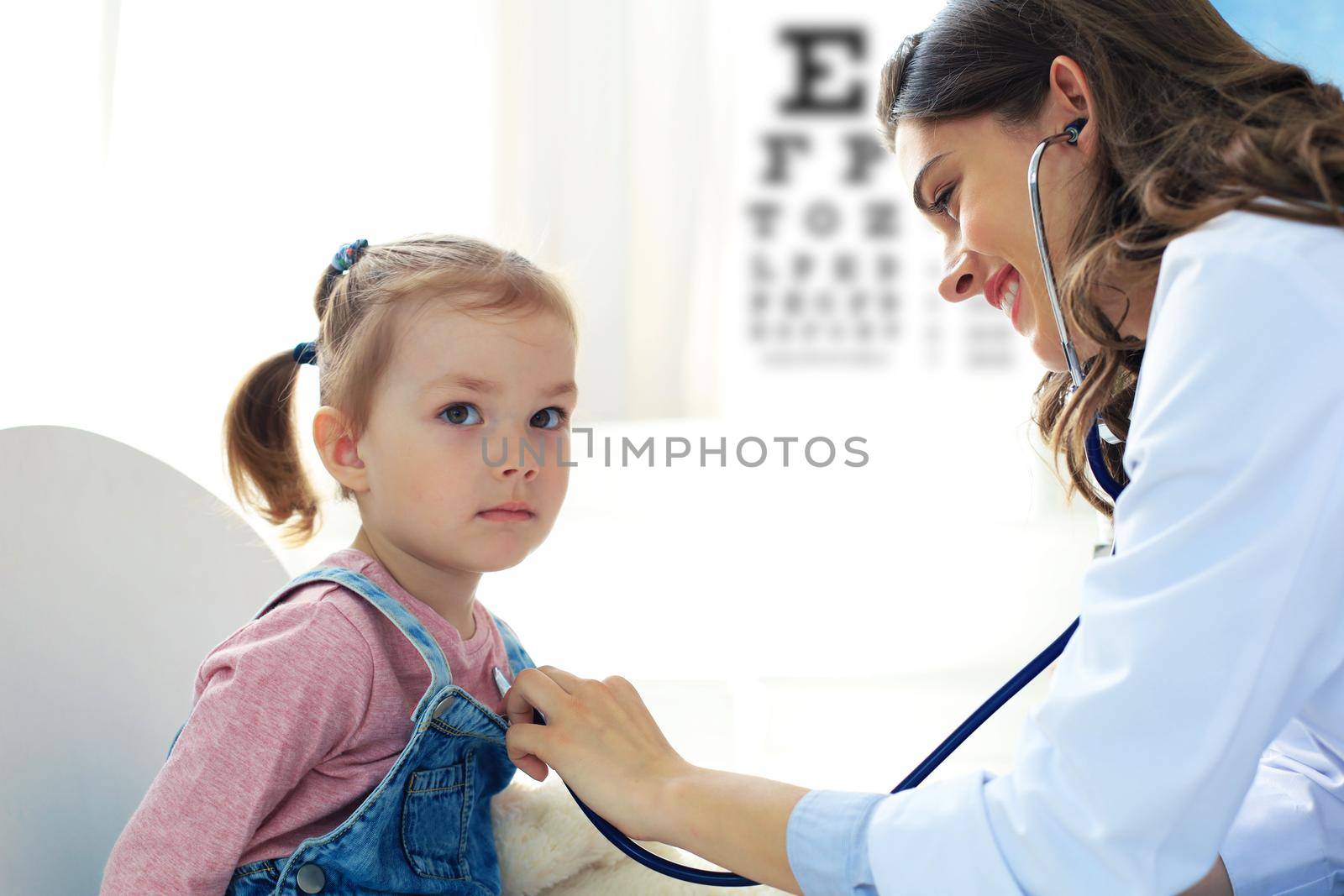 Little girl at the doctor for a checkup. Doctor woman auscultate the heartbeat of the child. by tsyhun