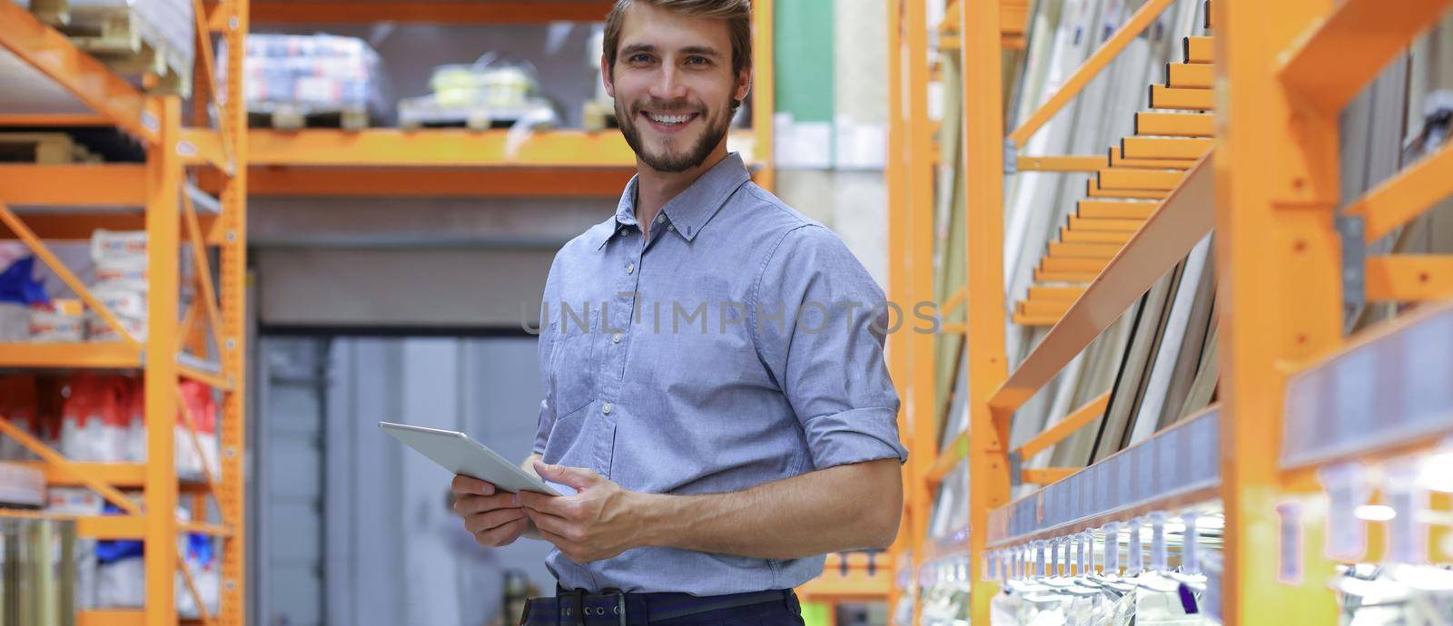 portrait of a smiling young warehouse worker working in a cash and carry wholesale store. by tsyhun