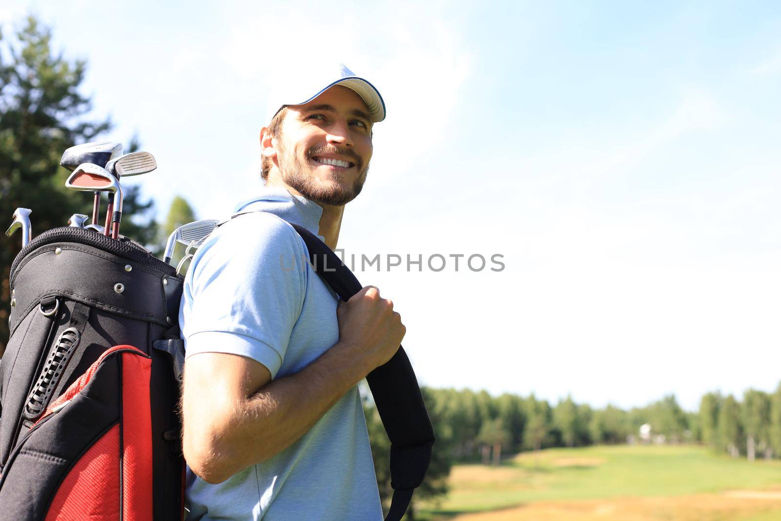 Golf player walking and carrying bag on course during summer game golfing