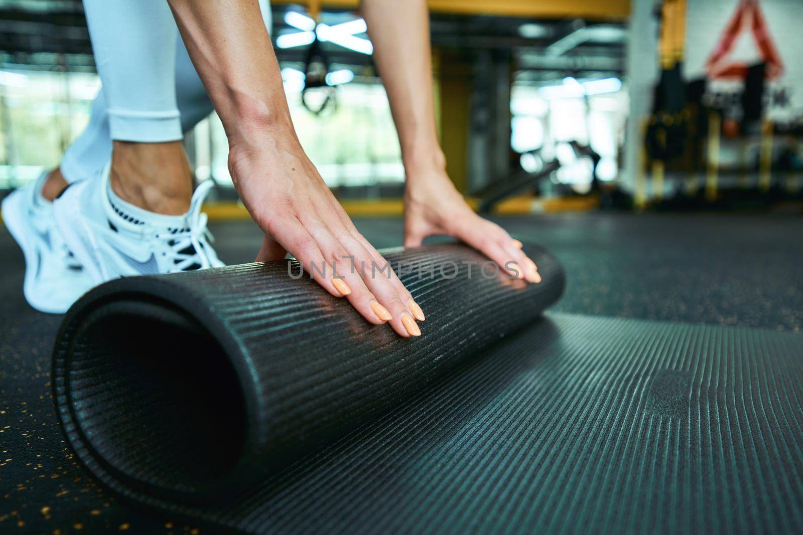 Cropped shot of a fitness woman in sportswear rolling yoga mat while working out at gym. Sport, wellness and healthy lifestyle