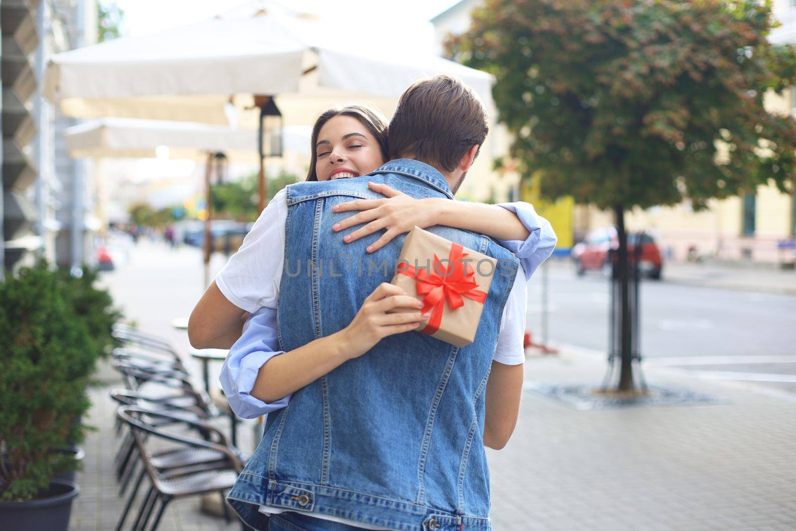 Image of attractive woman with present box giving hug to her man