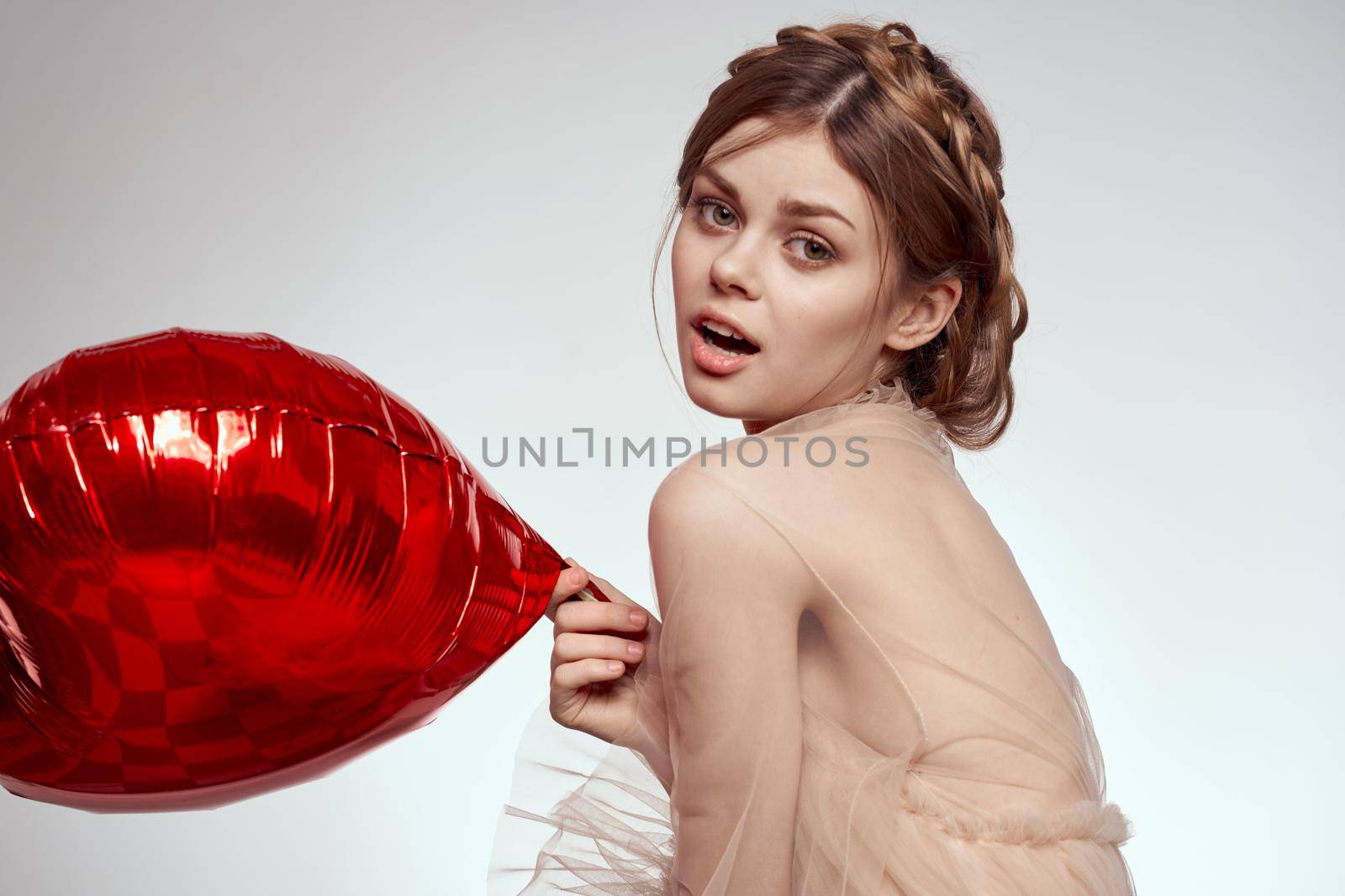 beautiful woman red heart in the hands of the balloon light background. High quality photo