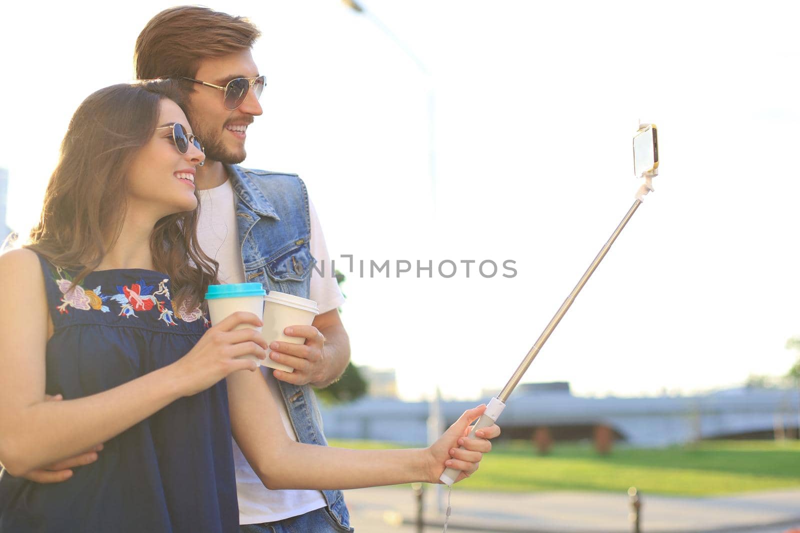 Beautiful lovely young couple walking at the city streets, hugging while taking a selfie. by tsyhun