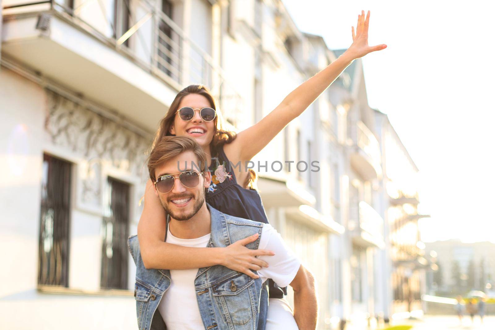 Handsome young man carrying young attractive woman on shoulders while spending time together outdoors. by tsyhun