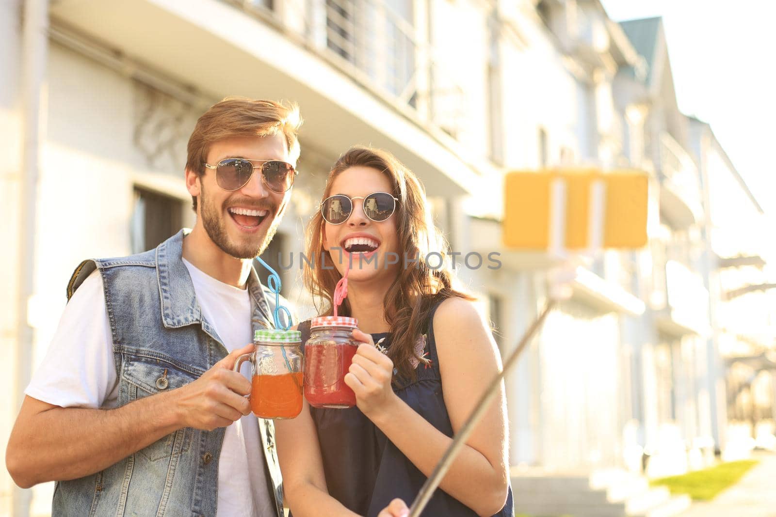 Beautiful lovely young couple walking at the city streets, hugging while taking a selfie