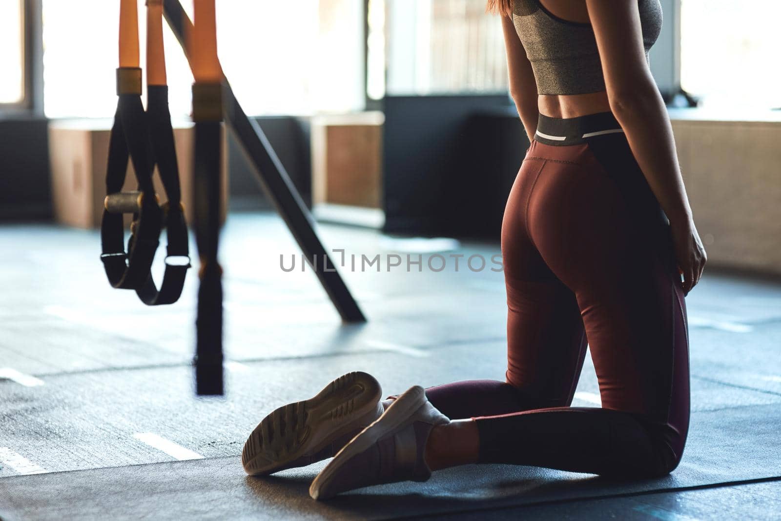 Cropped shot of athletic woman in sportswear exercising on the floor at gym, kneeling down. Sport, wellness and healthy lifestyle