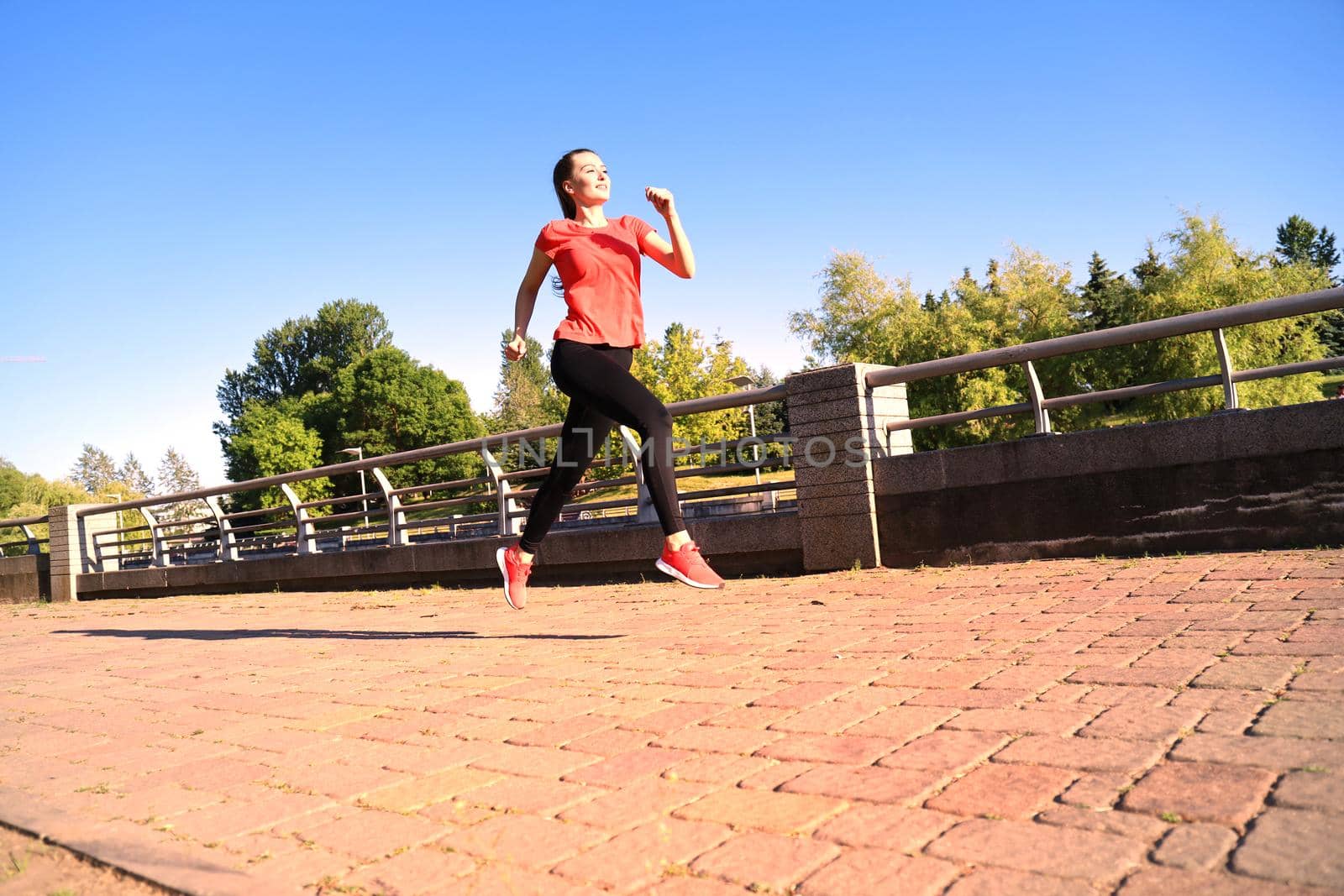 Beautiful young woman in sports clothing running while exercising outdoors