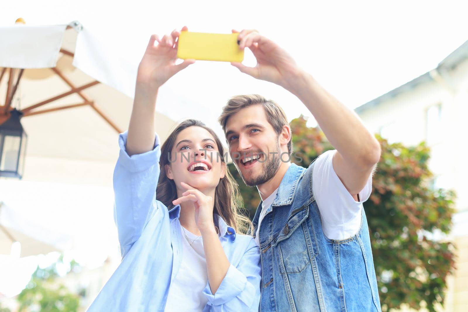 Beautiful lovely young couple walking at the city streets, hugging while taking a selfie. by tsyhun