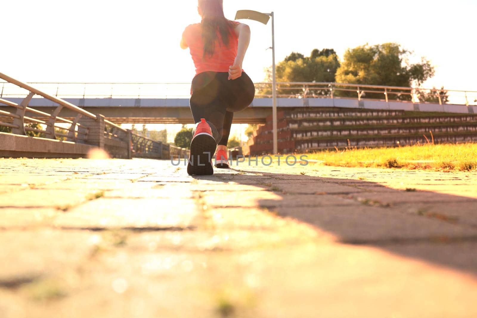 Photo of young fitness girl in sports clothing doing stretching exercises outdoors. by tsyhun
