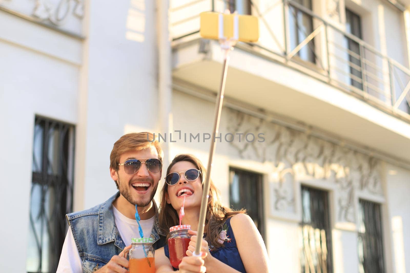 Beautiful lovely young couple walking at the city streets, hugging while taking a selfie