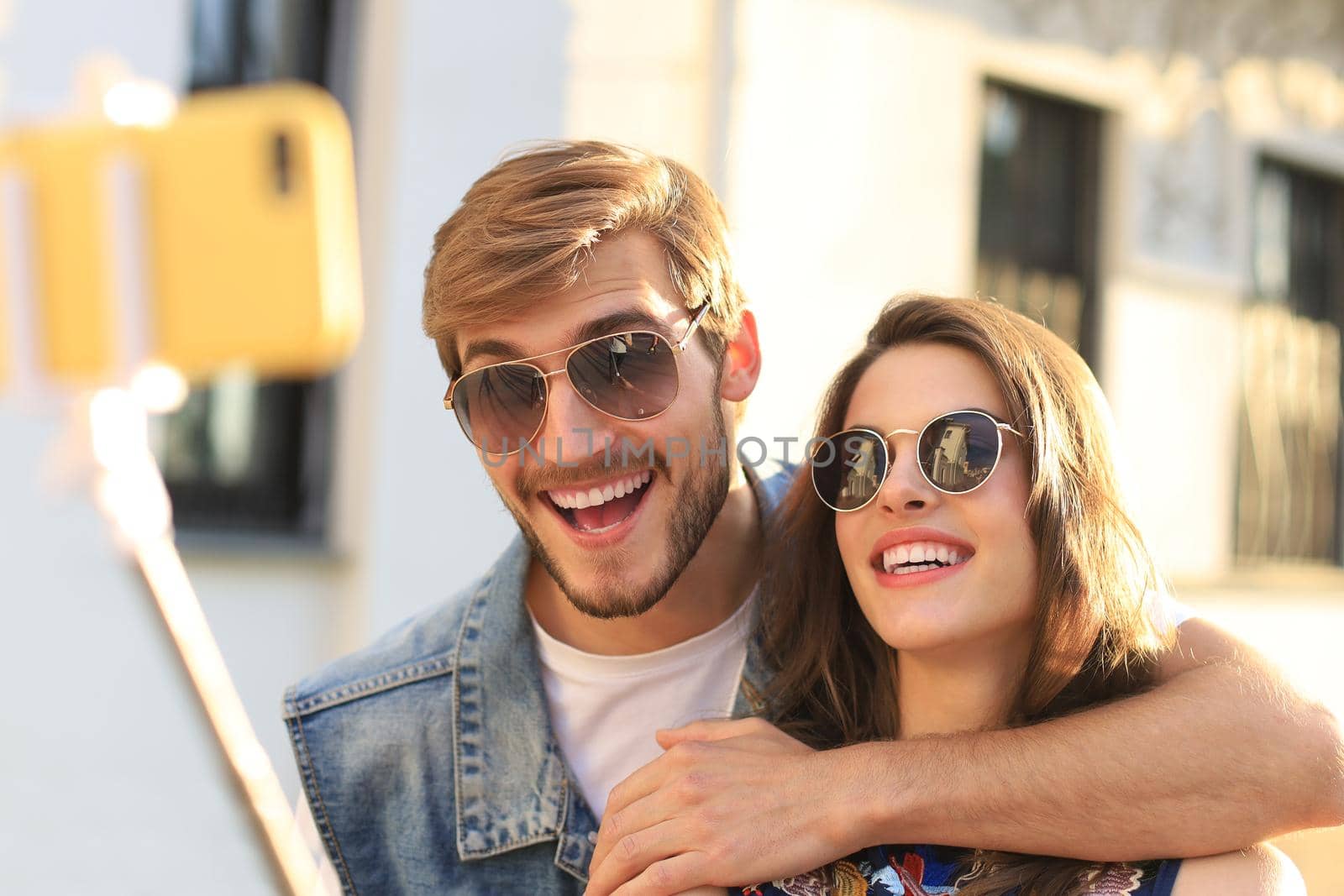 Beautiful lovely young couple walking at the city streets, hugging while taking a selfie