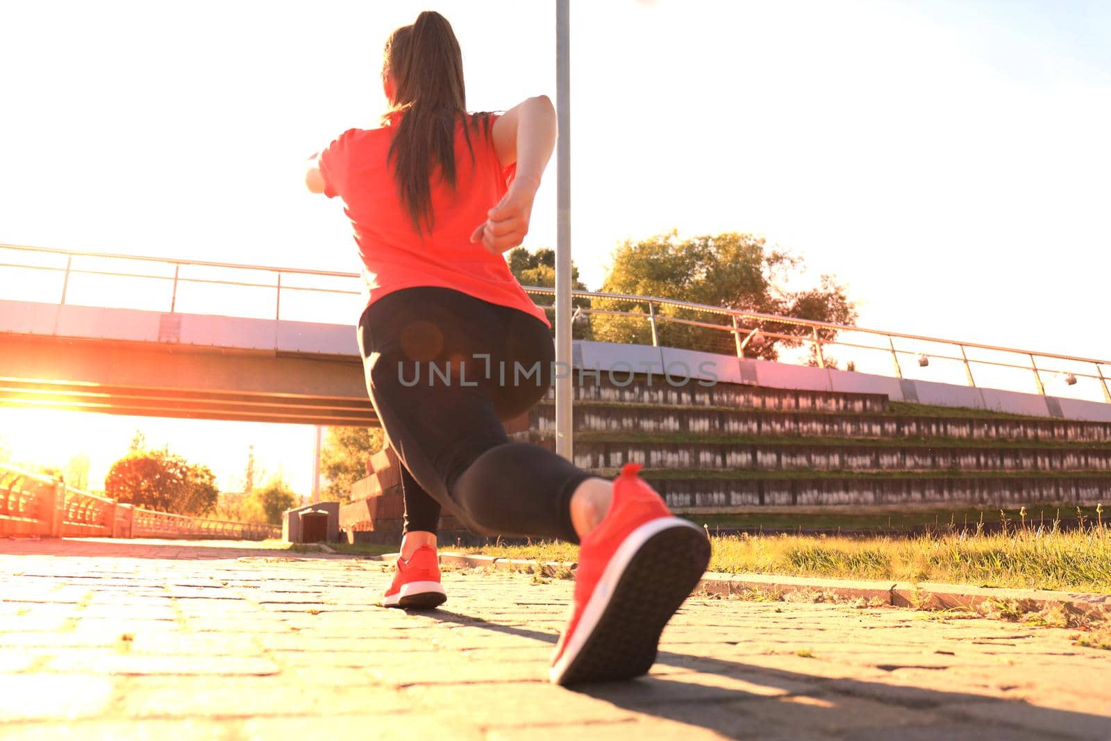 Photo of young fitness girl in sports clothing doing stretching exercises outdoors. by tsyhun