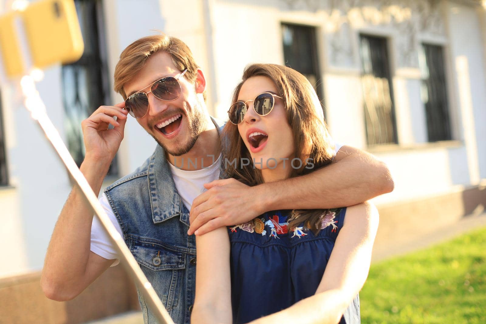 Beautiful lovely young couple walking at the city streets, hugging while taking a selfie