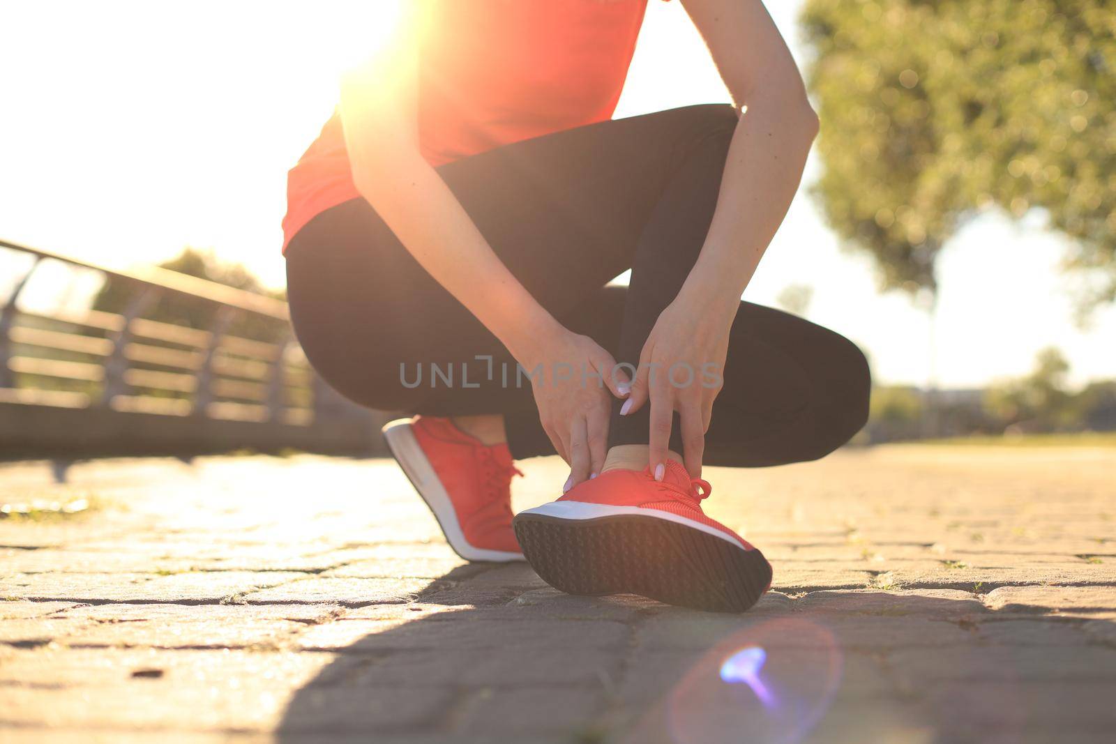 Sport woman - runner holding painful sprained ankle in pain. Female athlete with joint or muscle soreness and problem feeling ache in her lower body