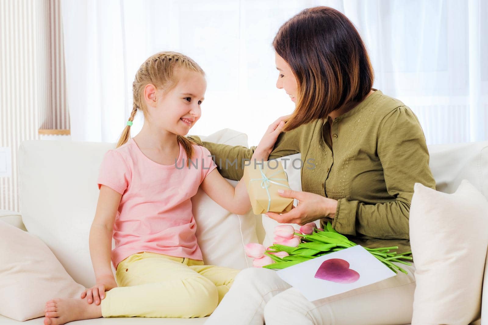 Smiling daughter giving mother festive presents on holidays