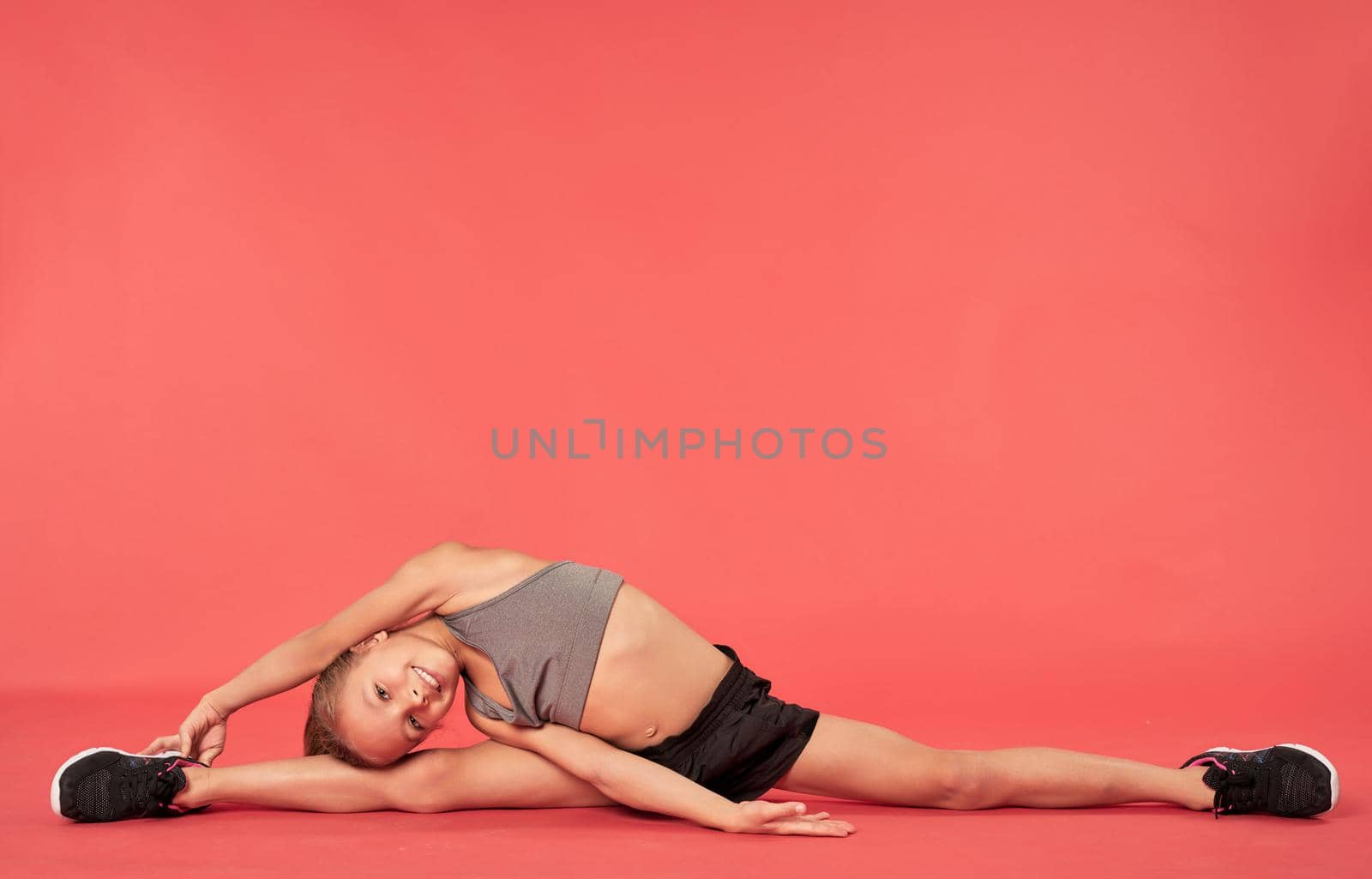 Cheerful girl in sportswear doing stretching exercise by friendsstock