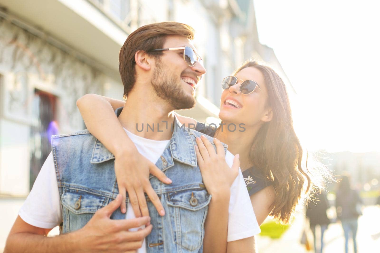 Beautiful young couple in love walking outdoors at the city street, hugging