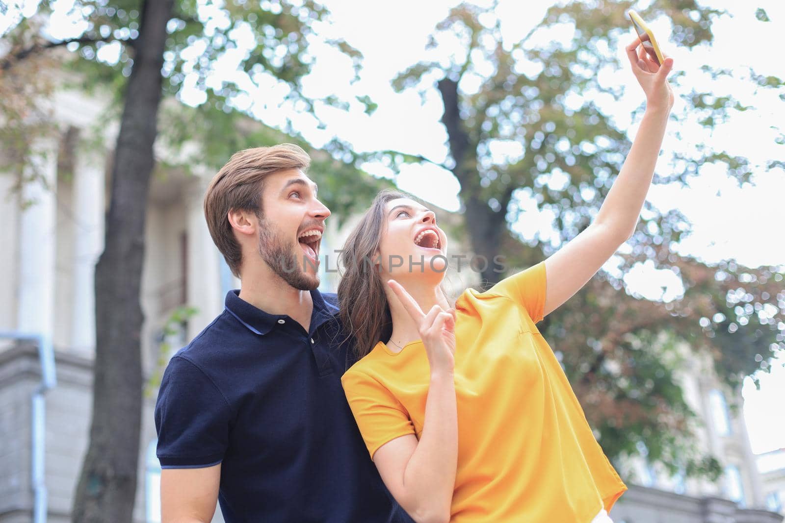 Beautiful lovely young couple walking at the city streets, taking a selfie