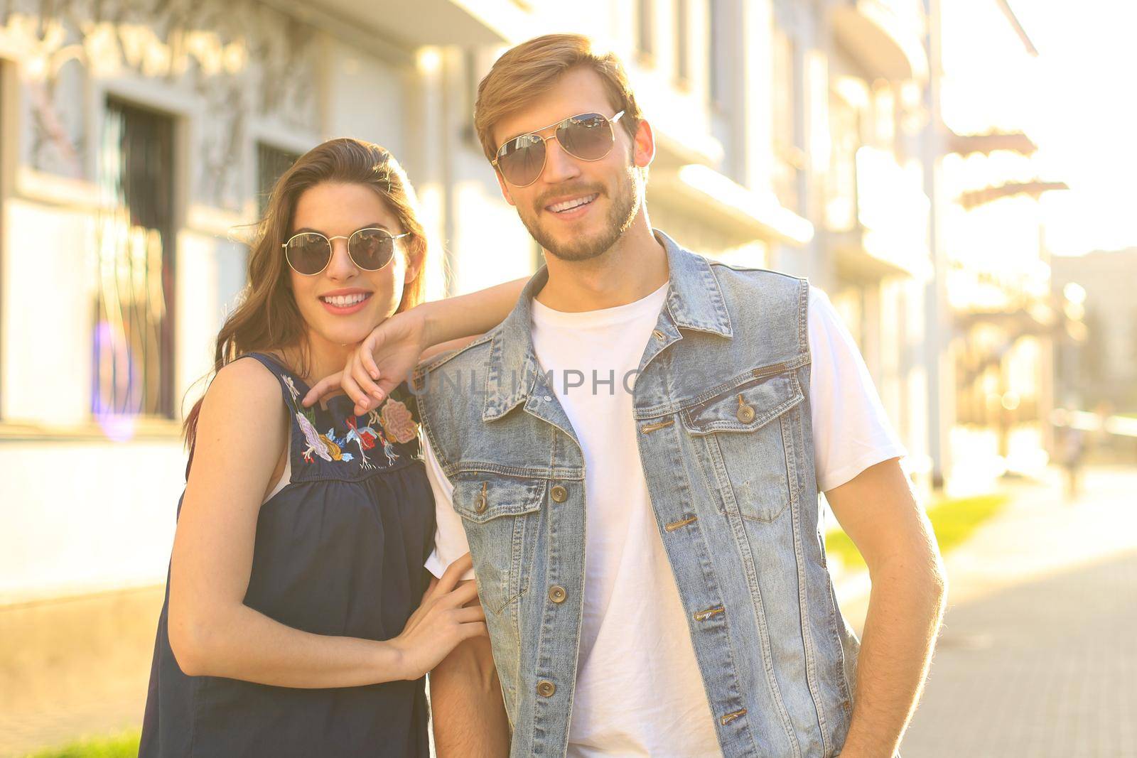 Image of lovely happy couple in summer clothes smiling and holding hands together while walking through city street