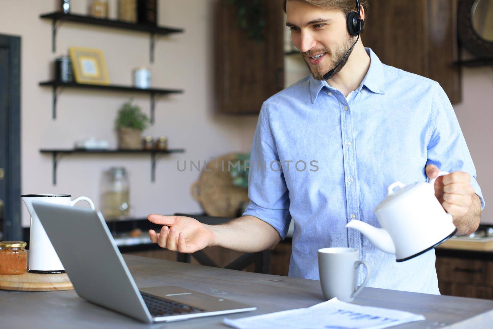 Smiling businessman greeting colleagues in video conference and negotiating distantly from home