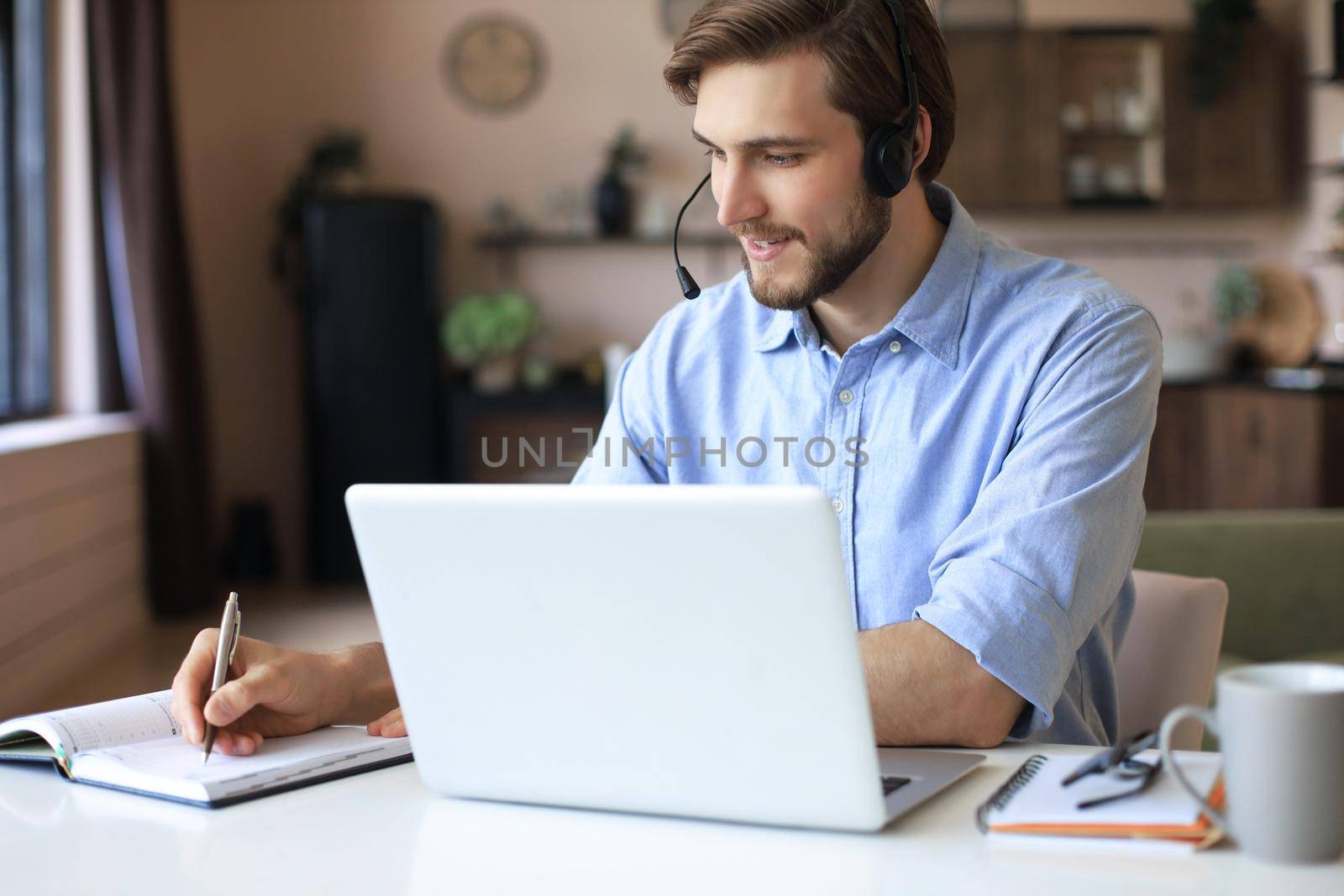 Confident man wearing headset speaking and watching business webinar training, listening to lecture