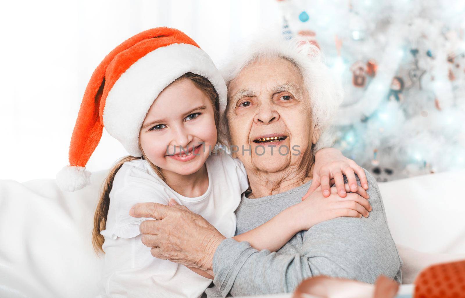 smiling granddaughter in santa hat hugging with grandma at Christmas