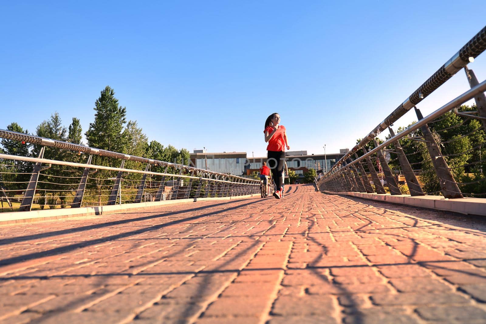 Beautiful young woman in sports clothing running while exercising outdoors