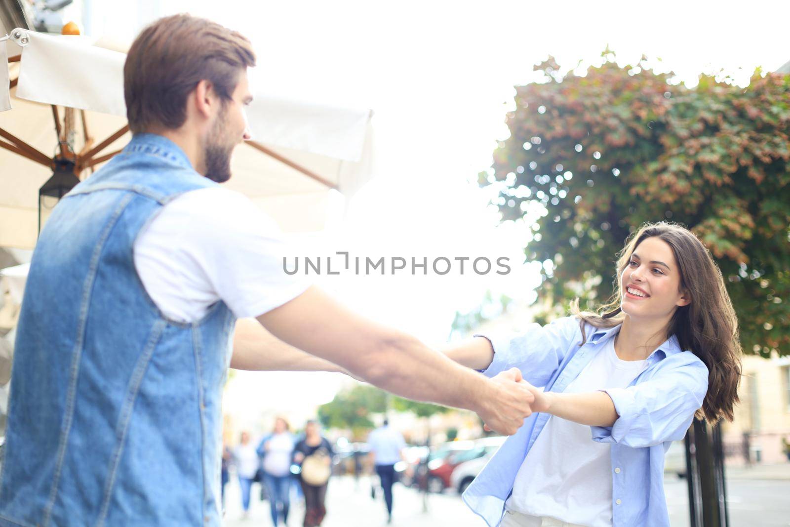 Beautiful young couple holding hands and spinning while standing on the city street