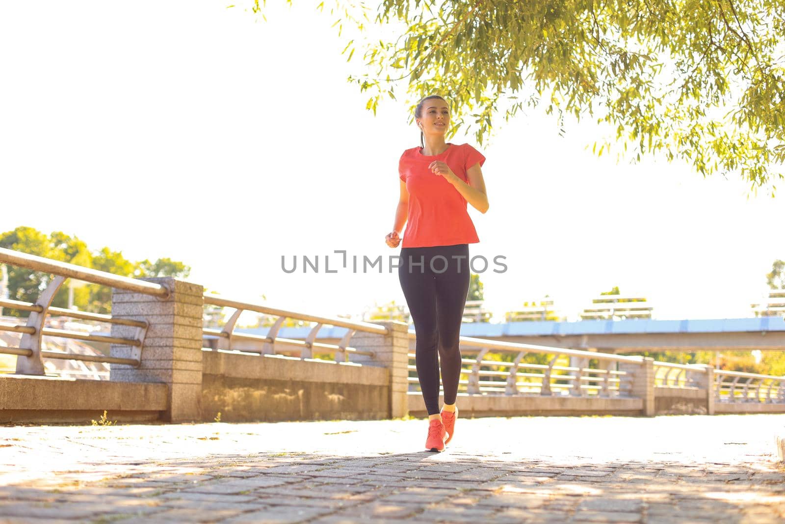 Beautiful young woman in sports clothing running while exercising outdoors