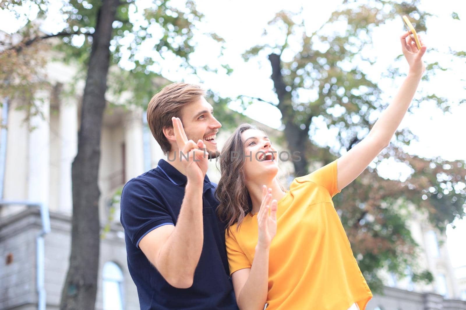 Beautiful lovely young couple walking at the city streets, hugging while taking a selfie