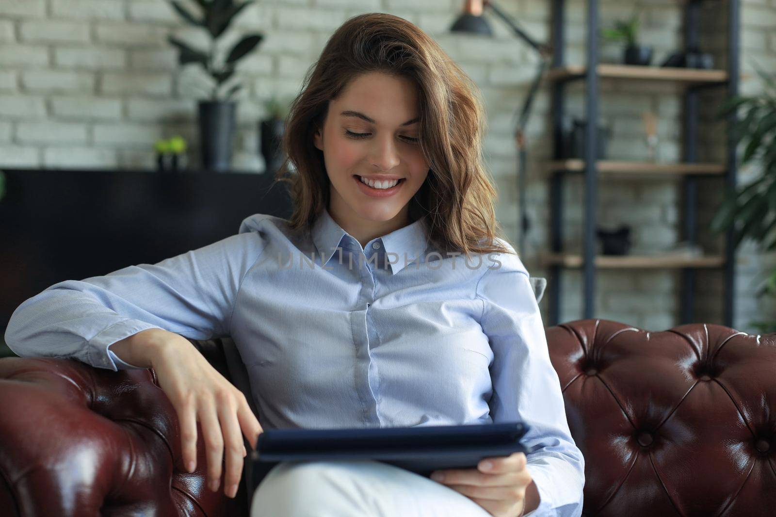 Young smiling woman with tablet pc on the sofa