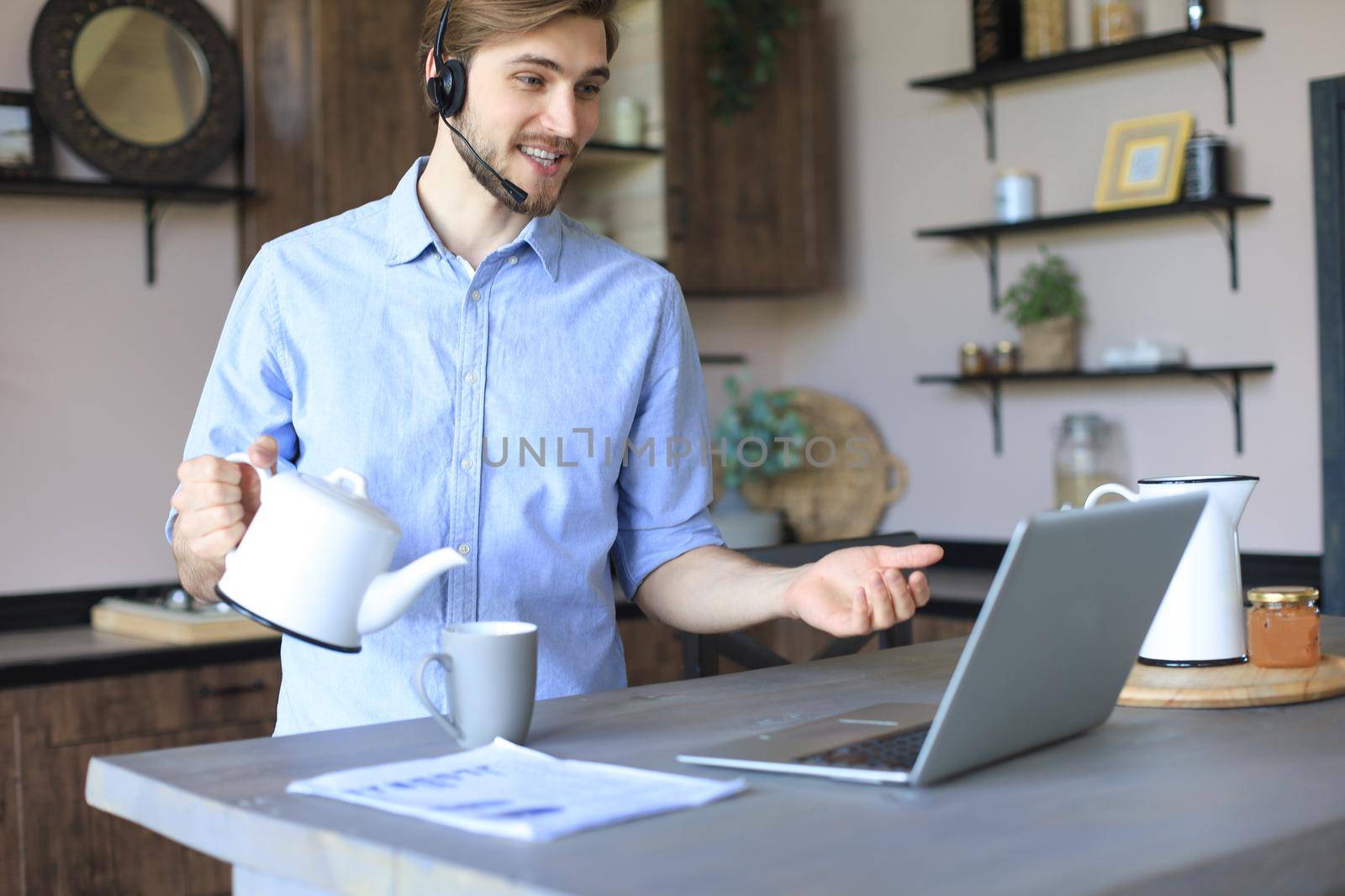 Smiling businessman greeting colleagues in video conference and negotiating distantly from home