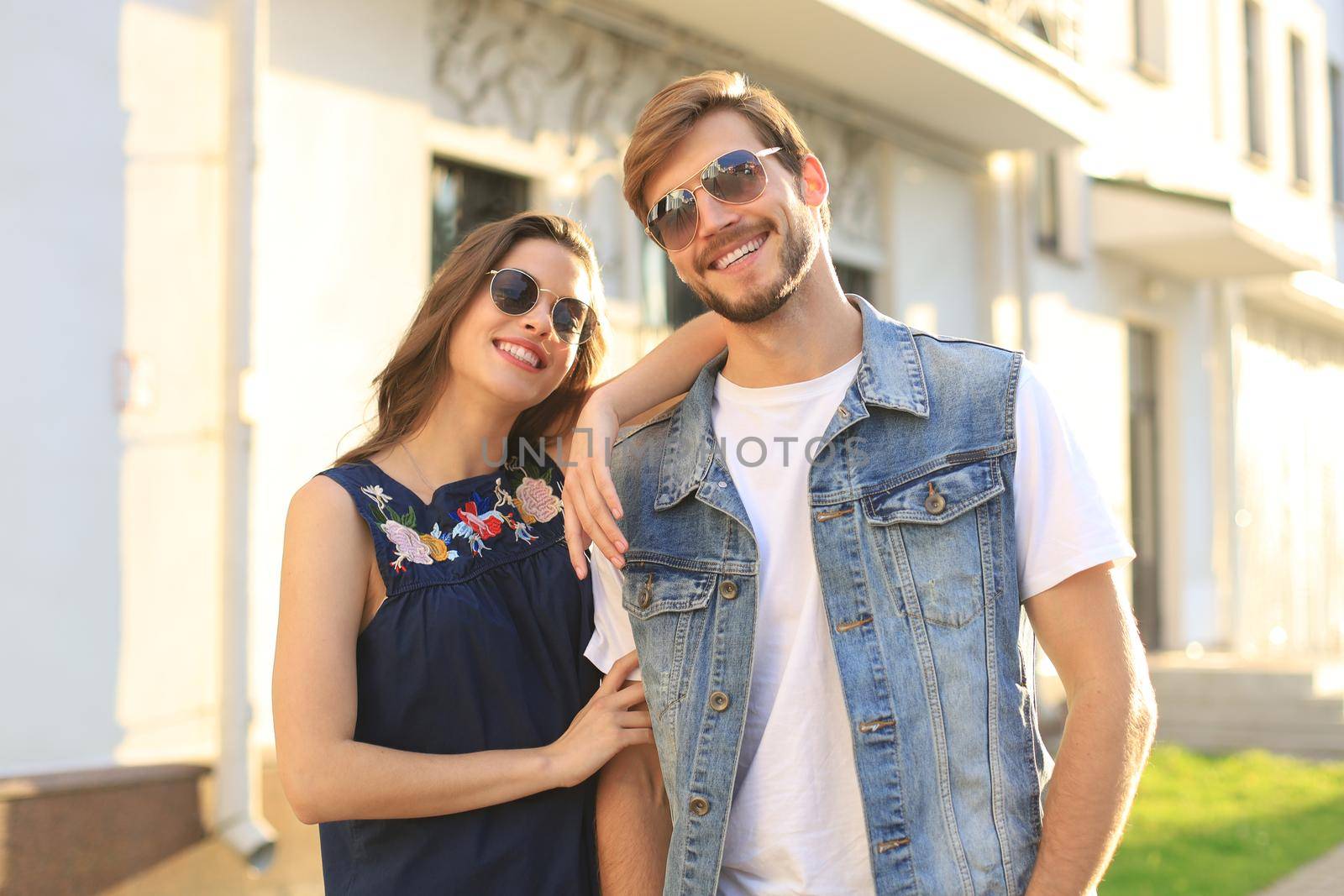 Image of lovely happy couple in summer clothes smiling and holding hands together while walking through city street