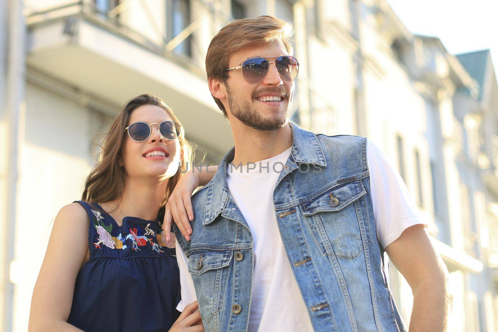 Image of lovely happy couple in summer clothes smiling and holding hands together while walking through city street