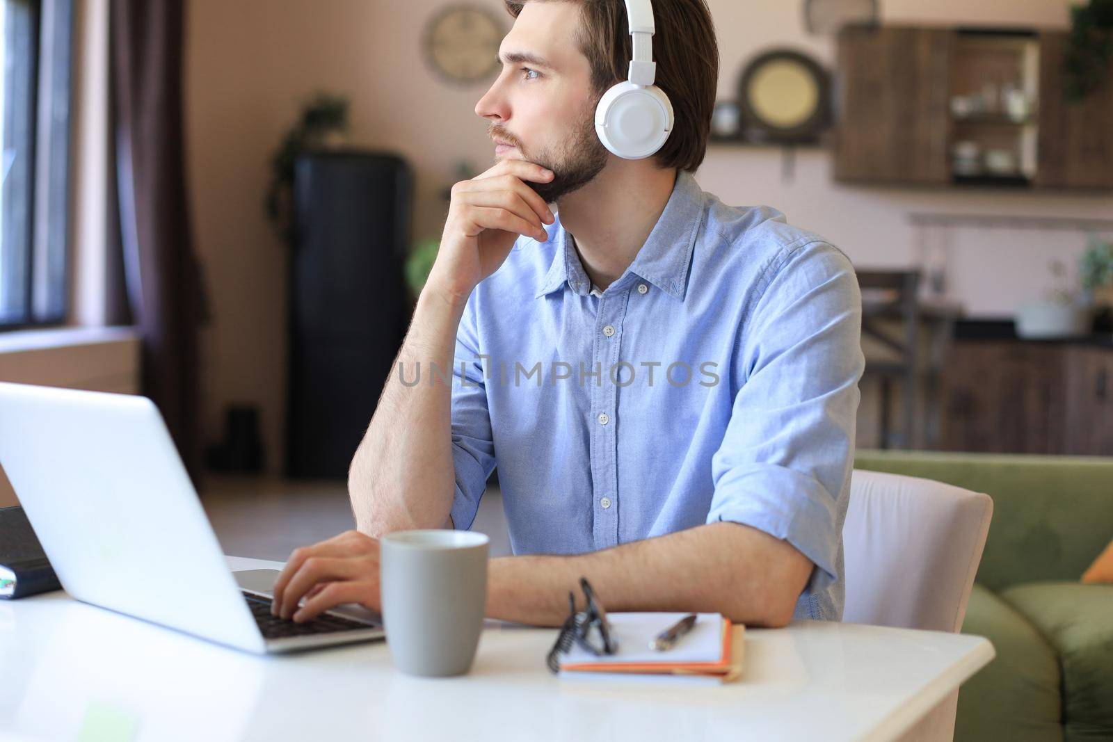 Happy young man in earphones working on laptop from home during self isolation