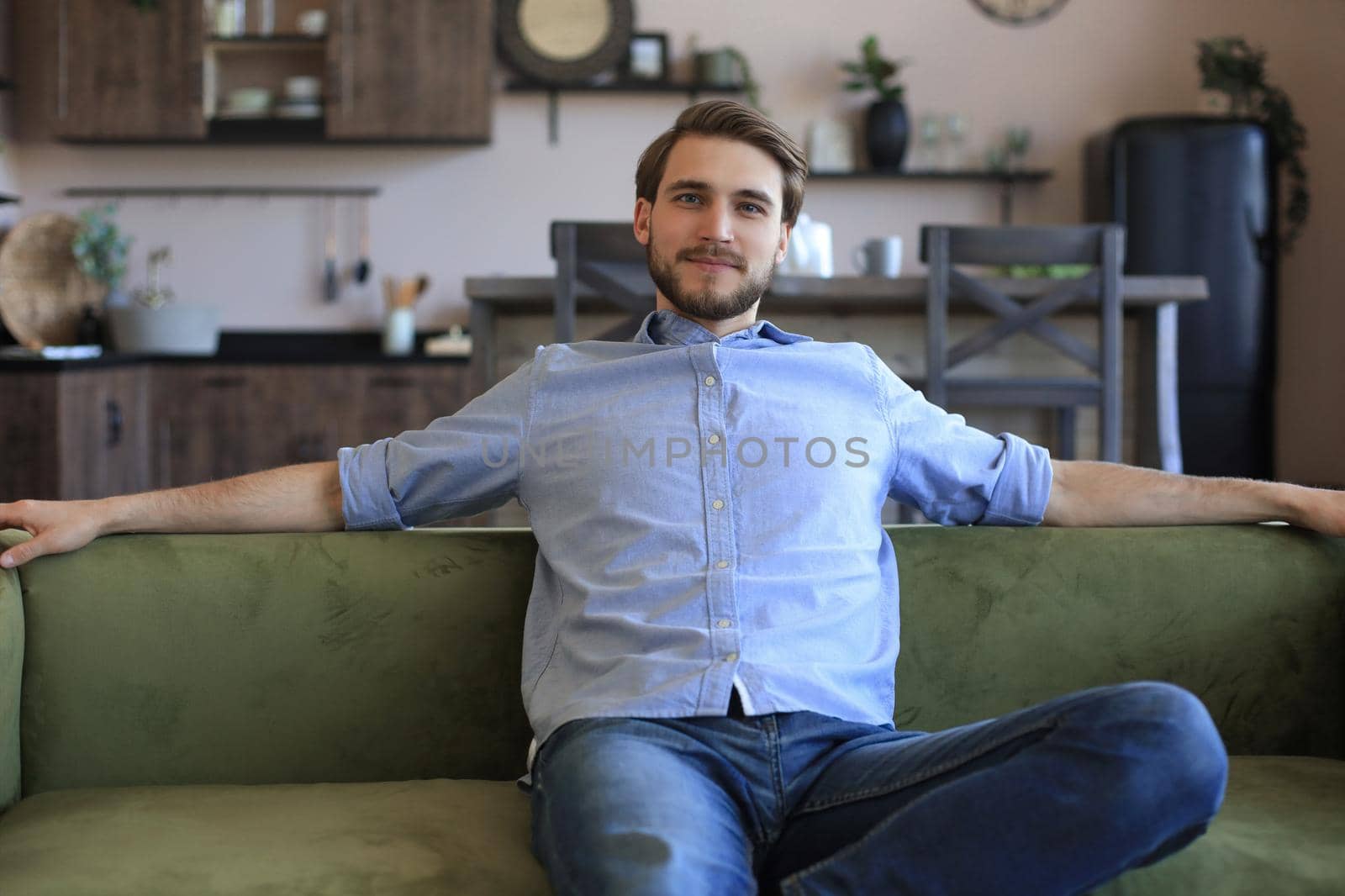 Handsome young business man is looking relaxed while sitting on the couch at home