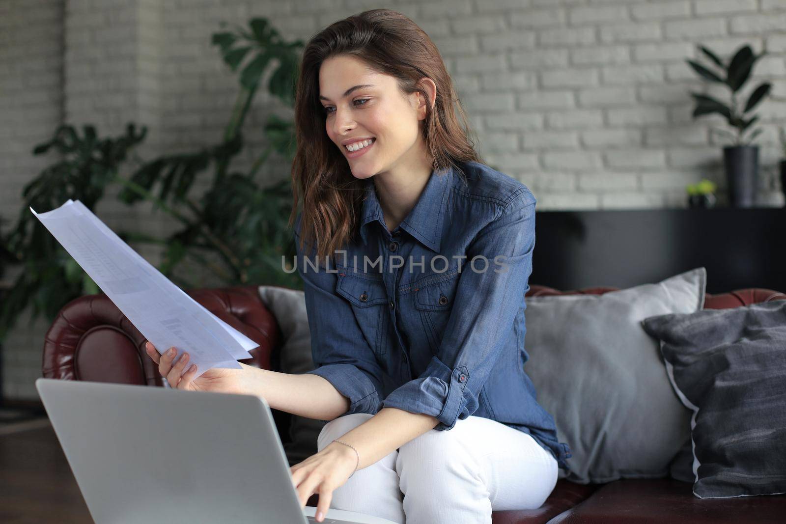 Smiling girl sit on couch watching webinar on laptop. Happy young woman study on online distant course
